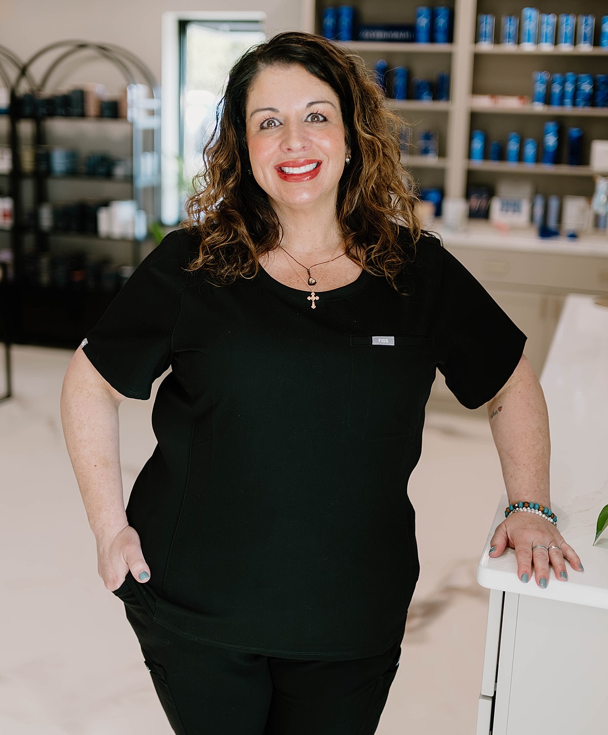 Smiling woman in black scrubs at salon.