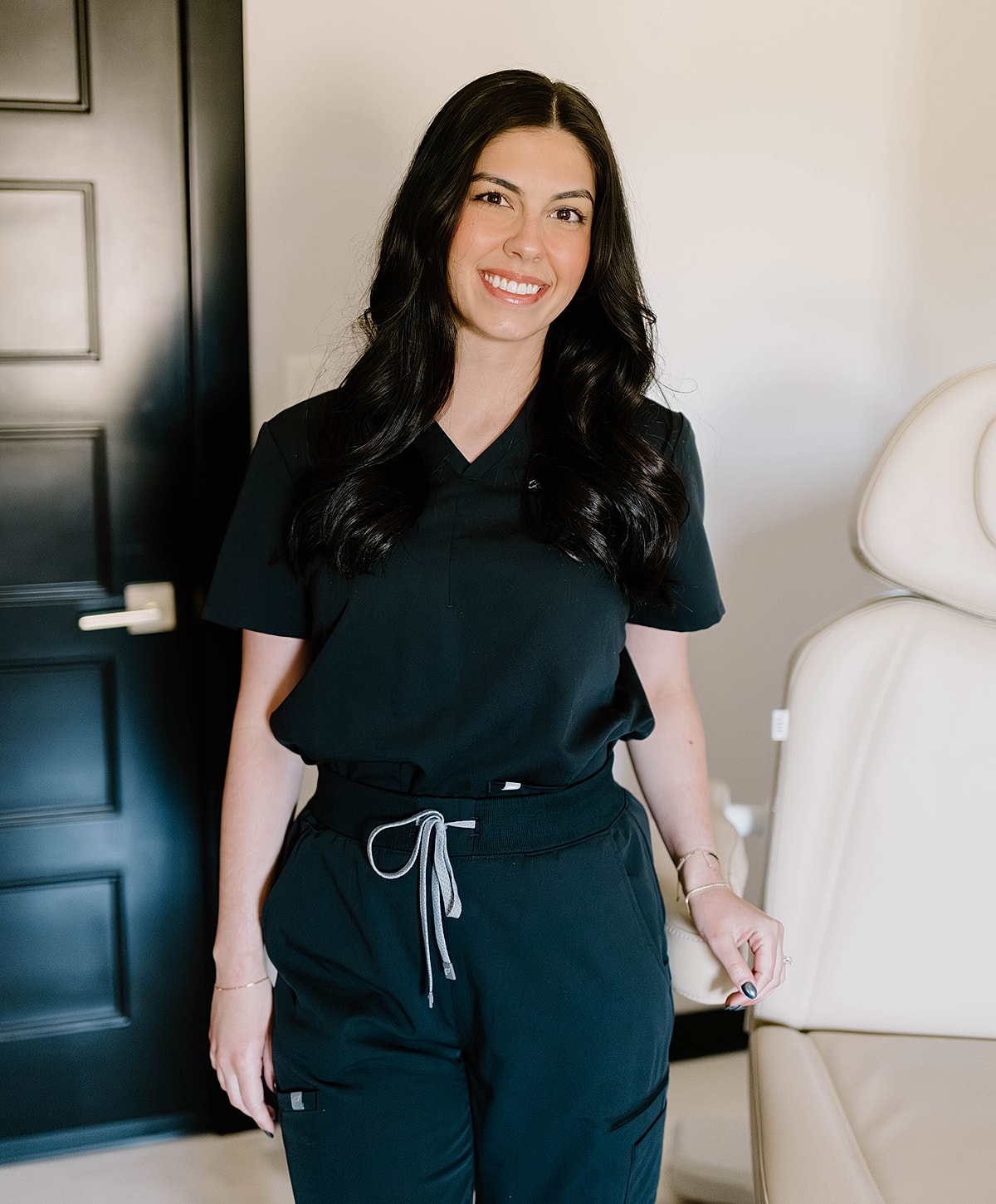 Young woman in scrubs smiling warmly.