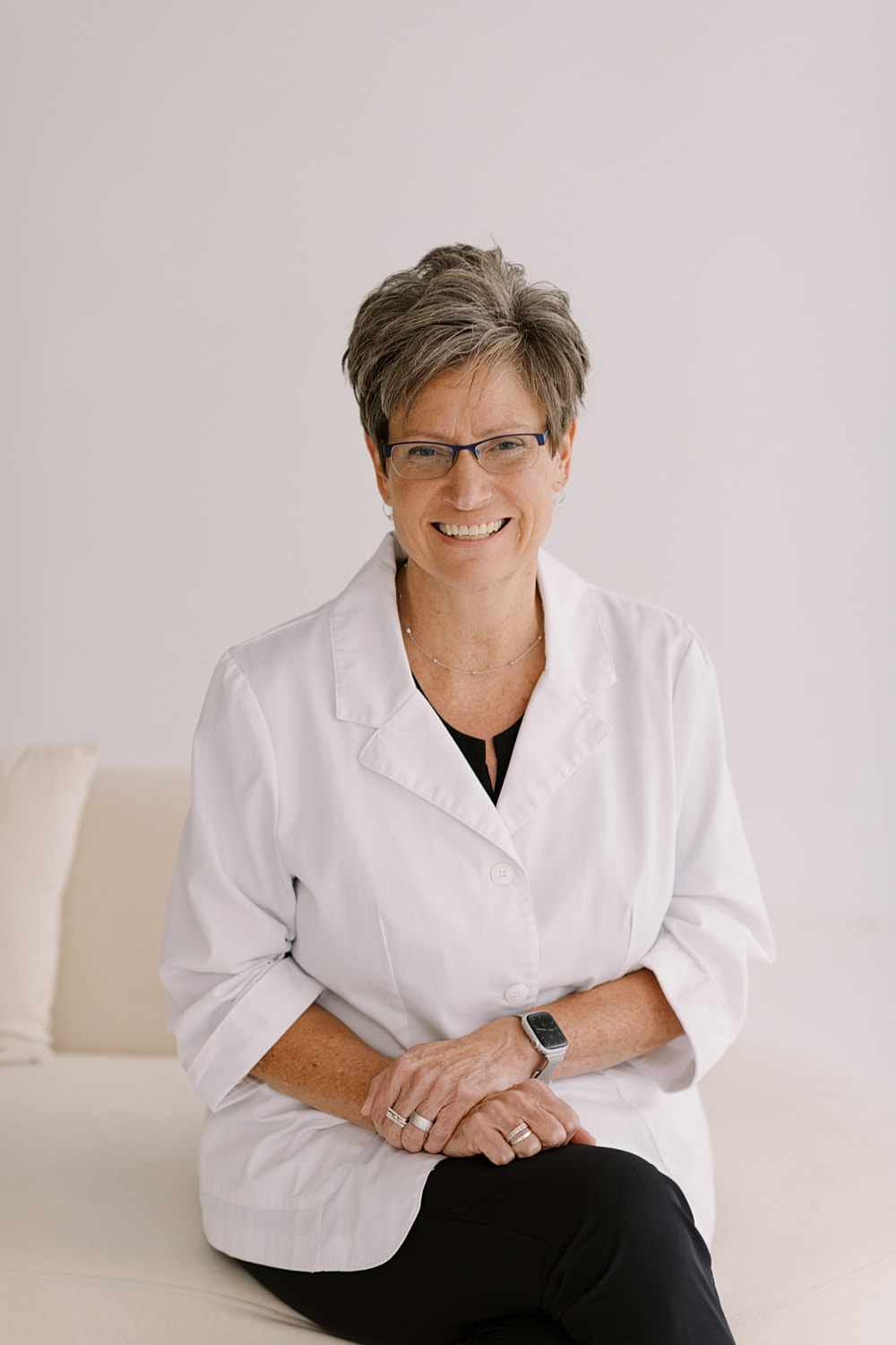 Smiling woman in a lab coat, posing indoors.