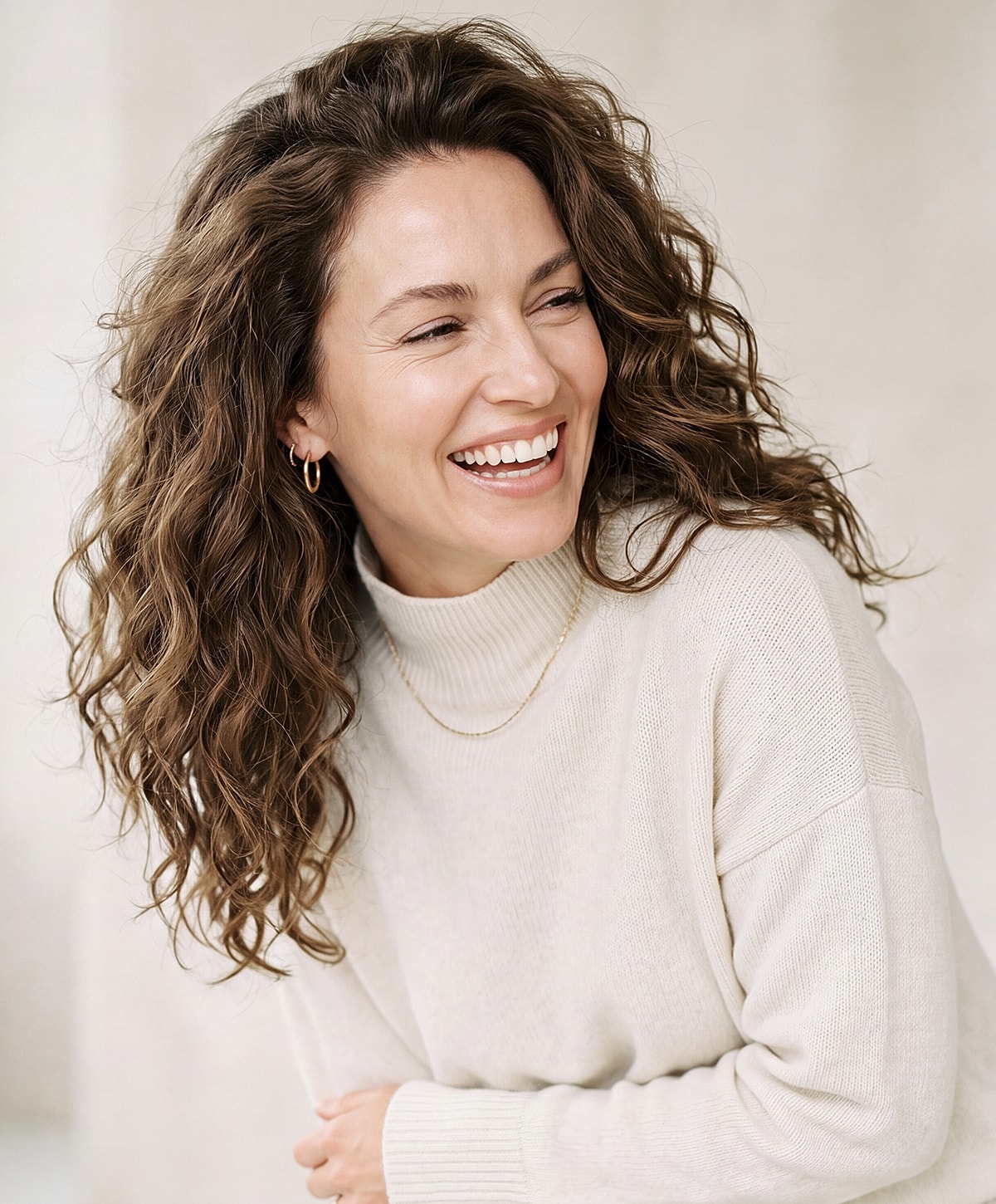 Smiling woman with curly hair in sweater.