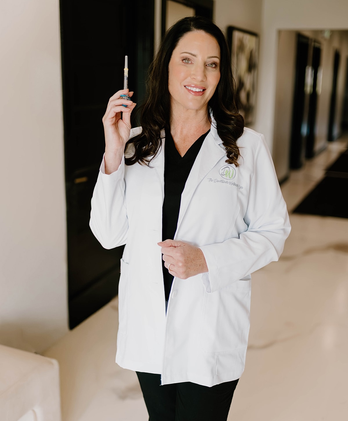 Woman in lab coat holding a syringe.