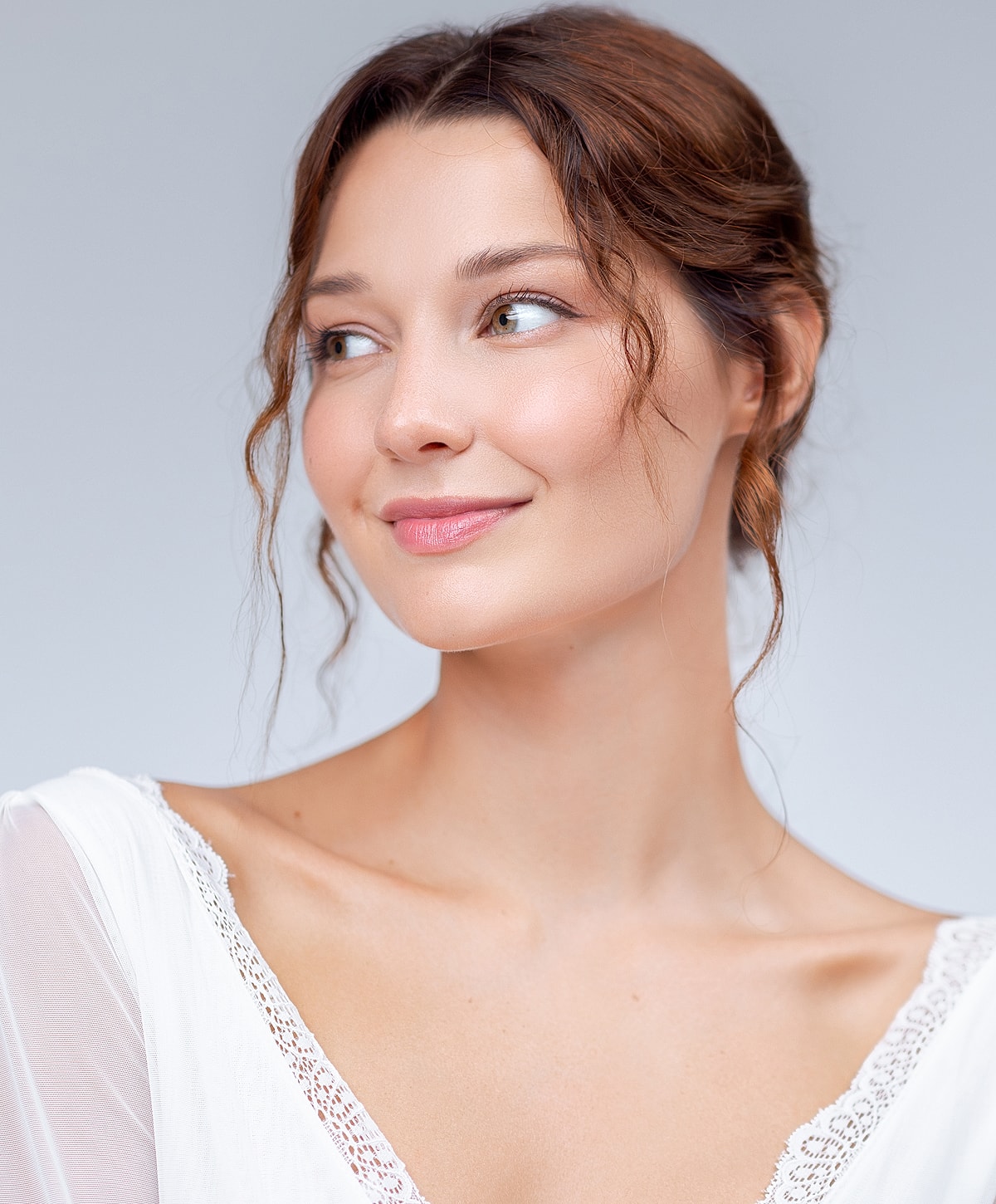 Smiling woman in white attire, soft background.