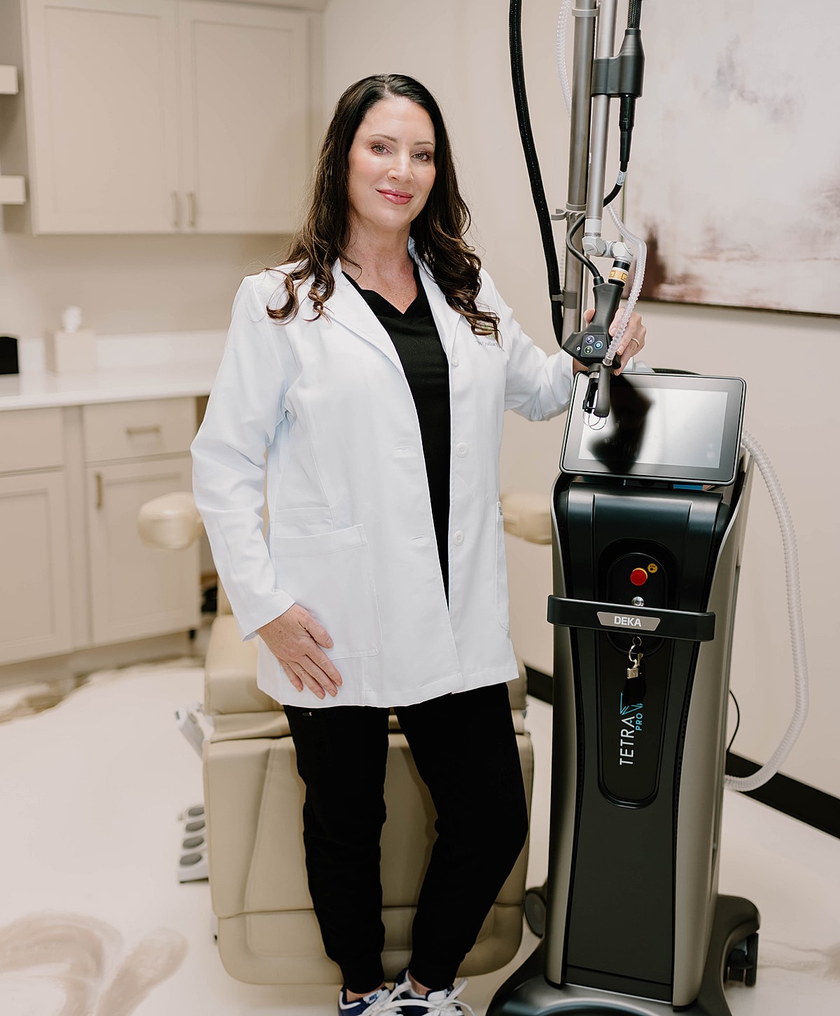 Female clinician beside medical equipment in office