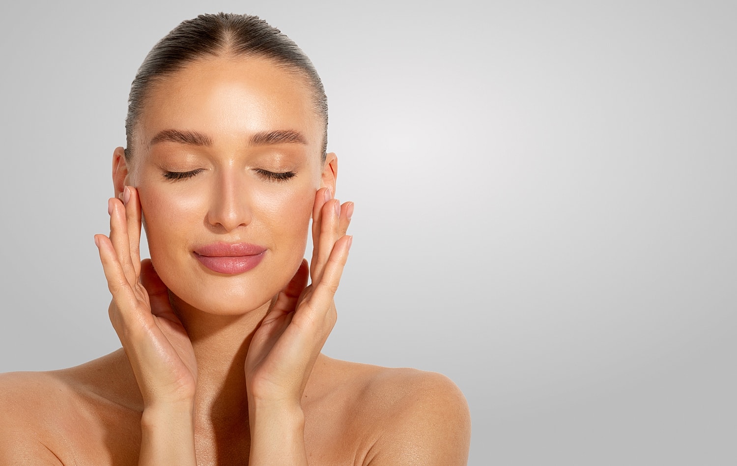Woman with glowing skin gently touching her face