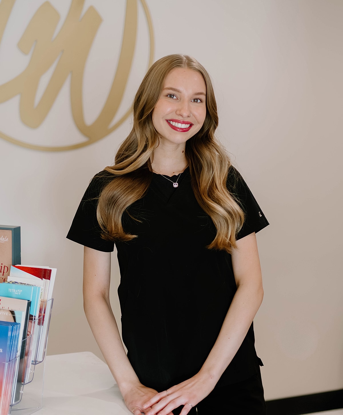 Smiling woman in black shirt at a reception desk.