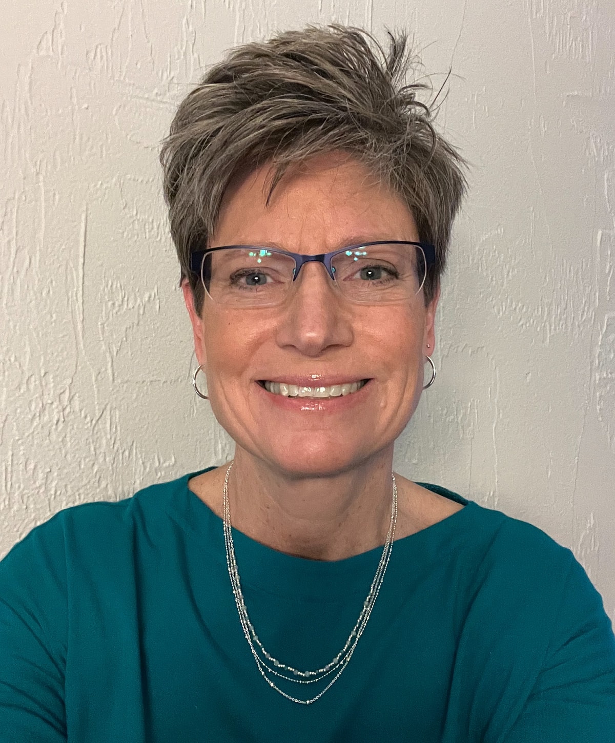 Smiling woman with short hair and glasses.