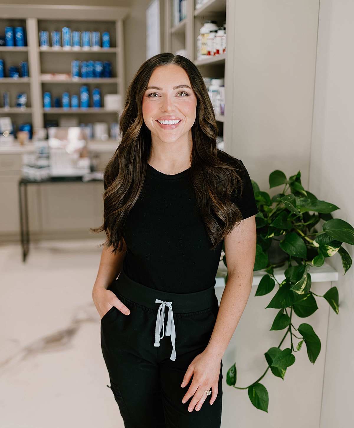 Smiling woman in a wellness setting with plants.