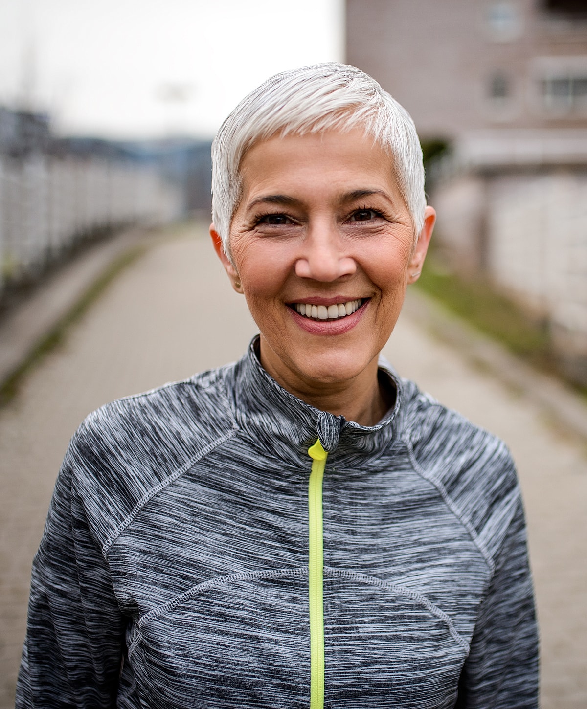 Smiling older woman in athletic clothing outdoors.