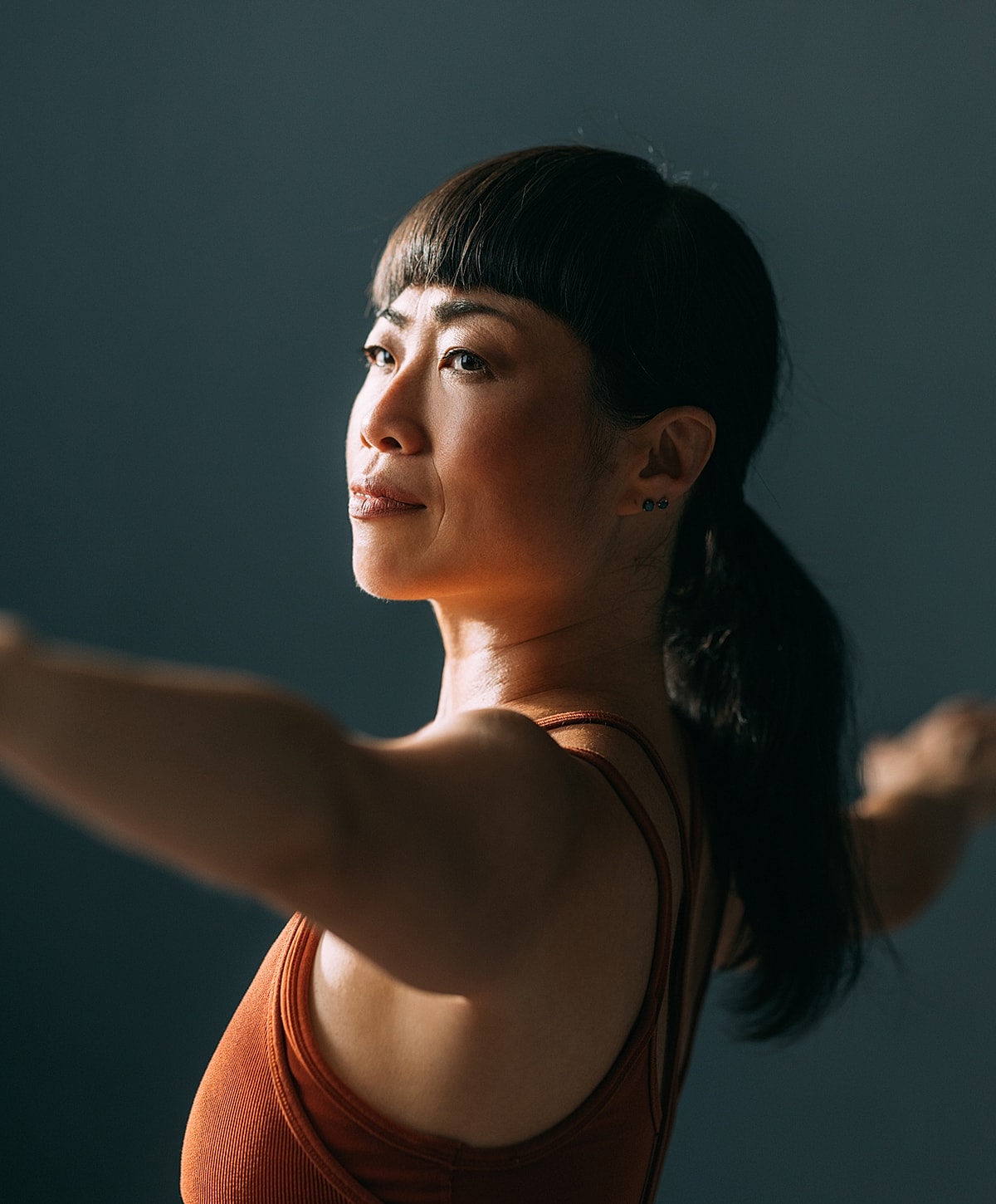 Woman in yoga pose against dark background.