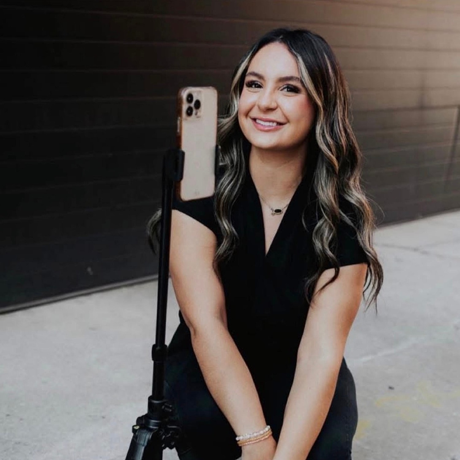 Smiling woman taking selfie with smartphone tripod.