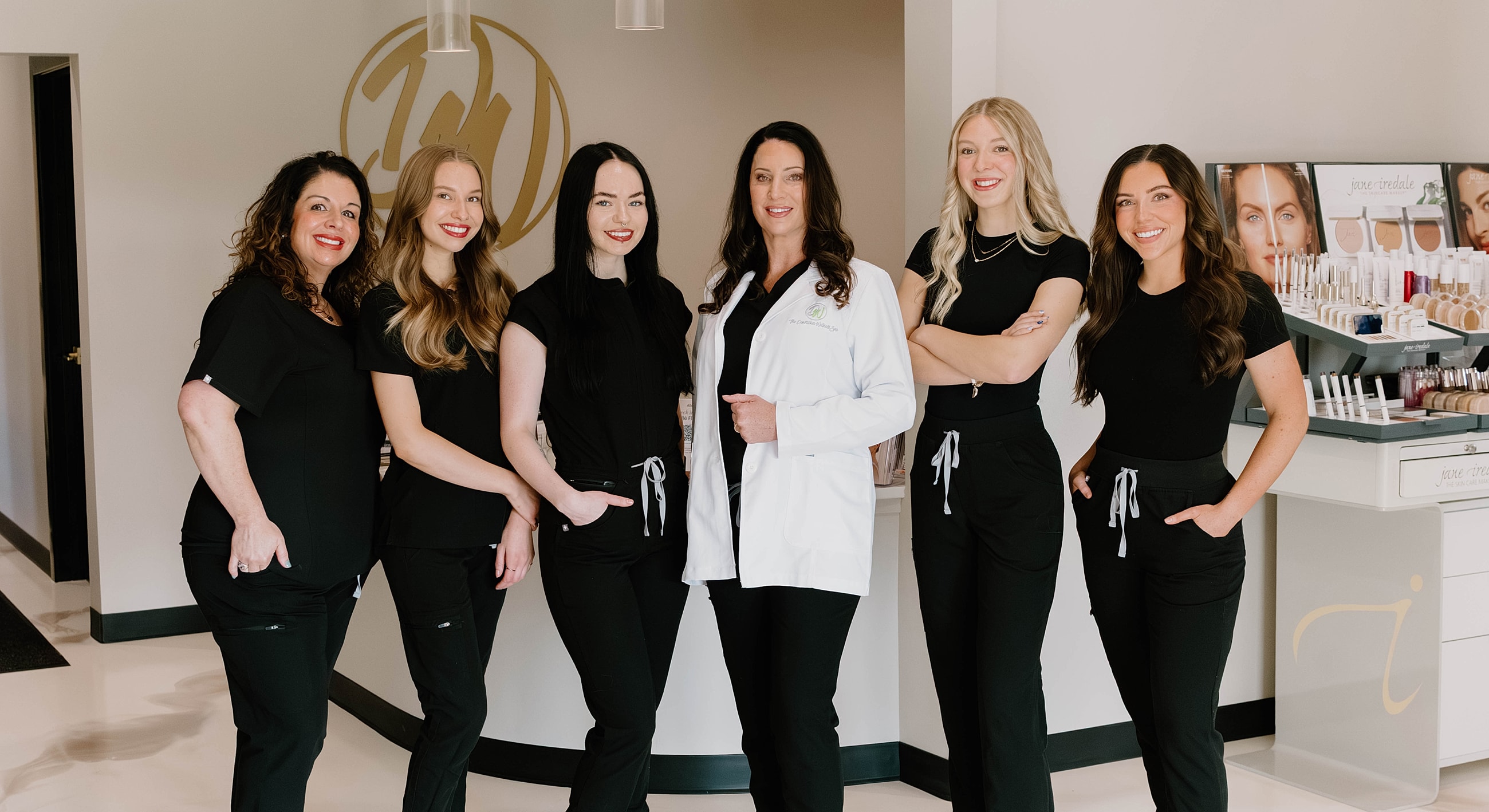 Four women in medical attire smiling together.