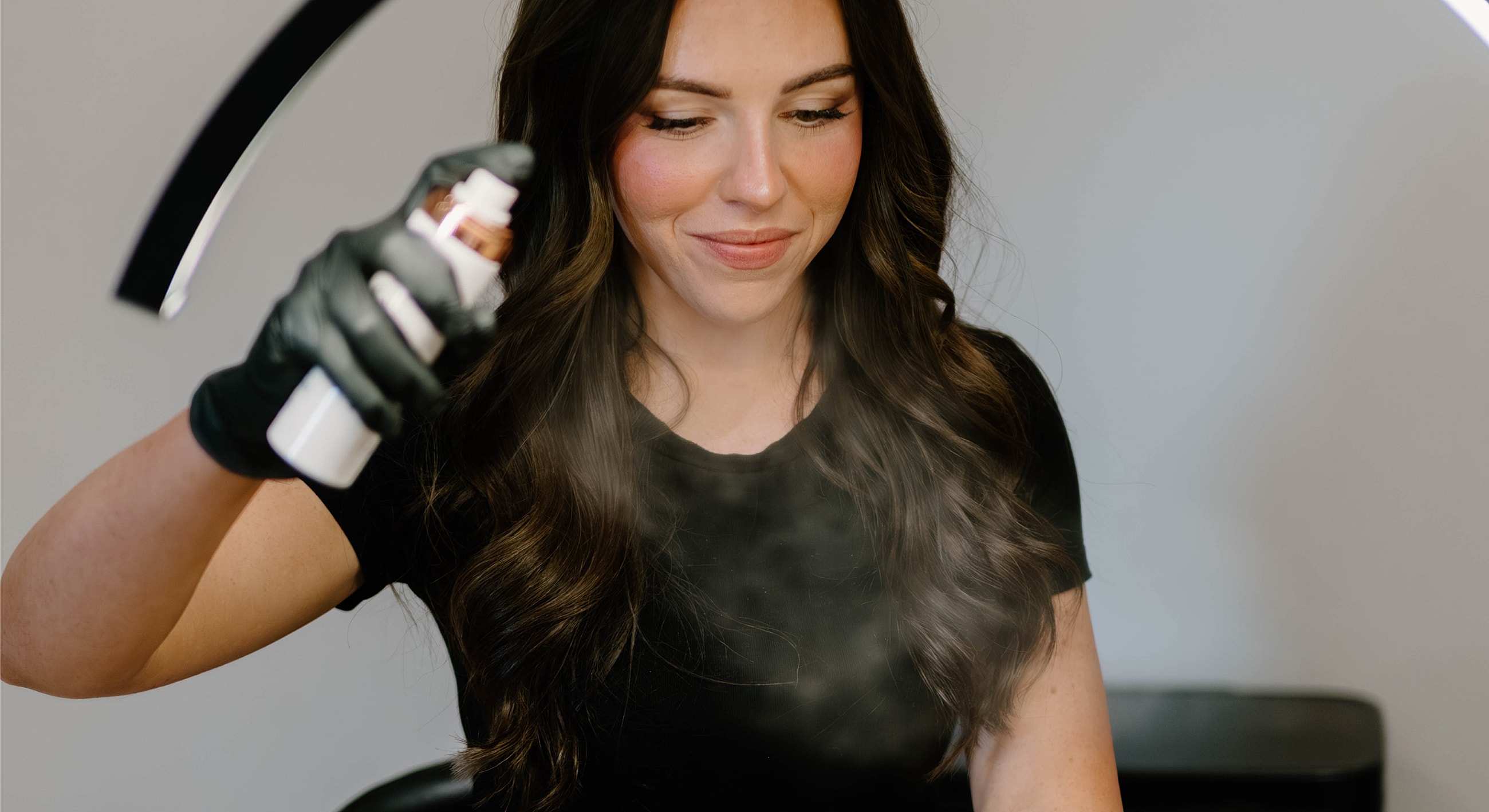Woman using spray product in beauty salon.