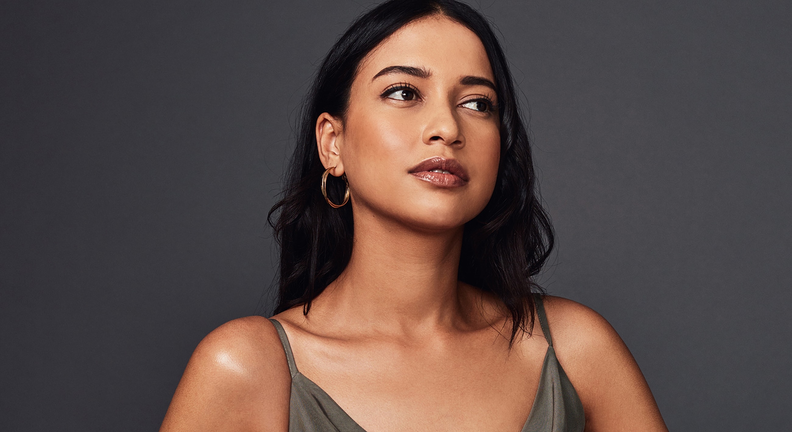 Woman with dark hair, wearing hoop earrings.