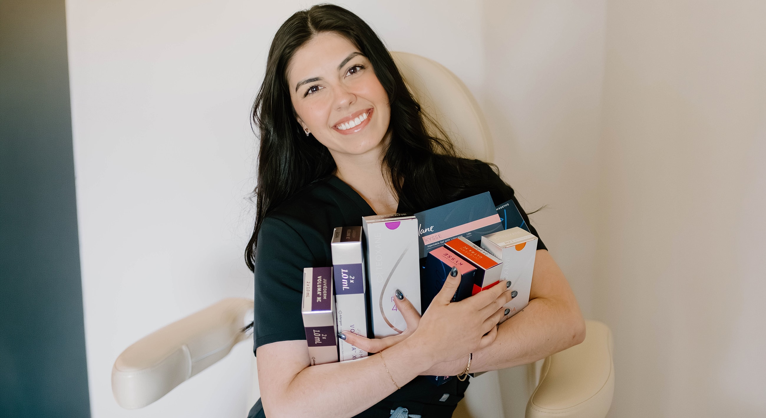 Woman holding various skincare products and smiling.