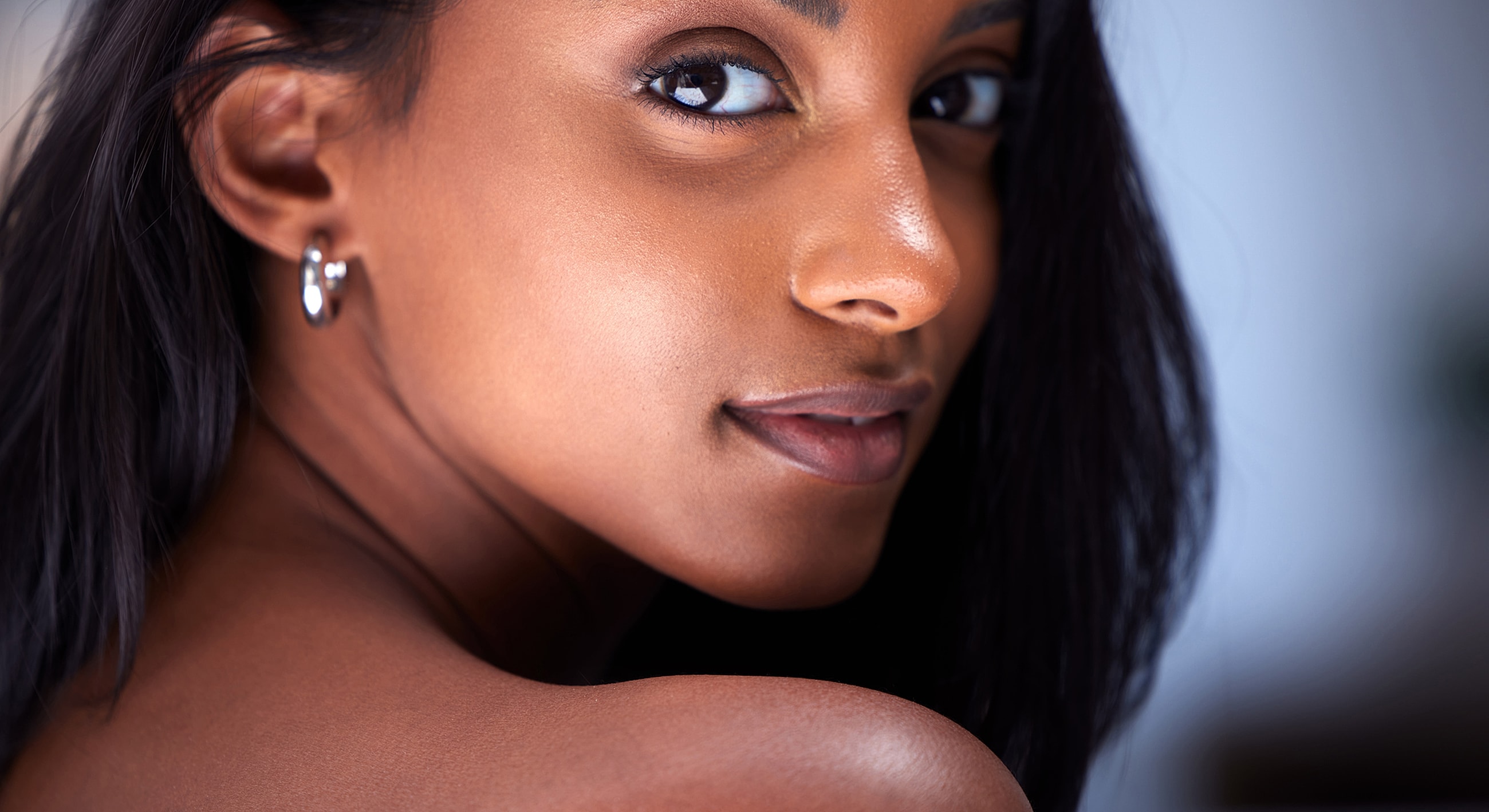 Portrait of a woman with dark hair and earrings.