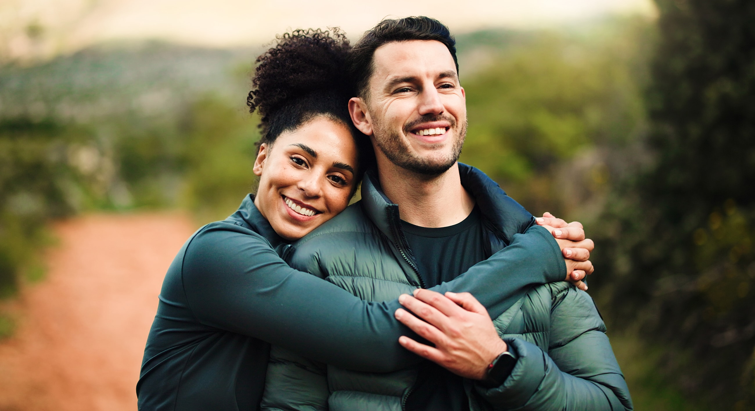 Couple hugging outdoors, smiling happily together.