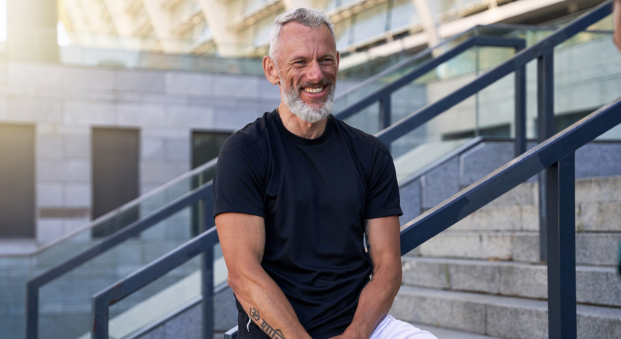 Smiling man sitting on stairs outdoors.